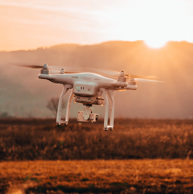 Drone in flight over open fields at sunset