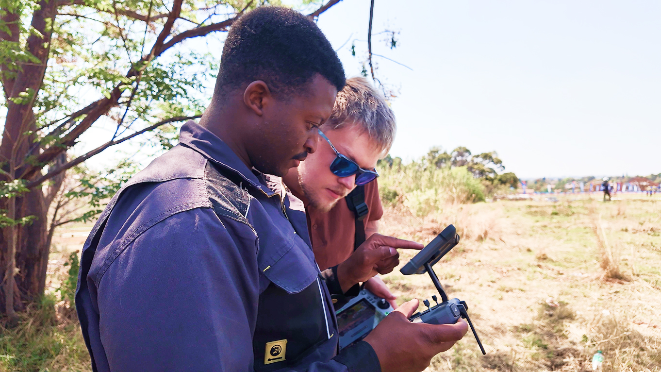 Two Berenith operators reviewing live drone footage on a remote controller in the field